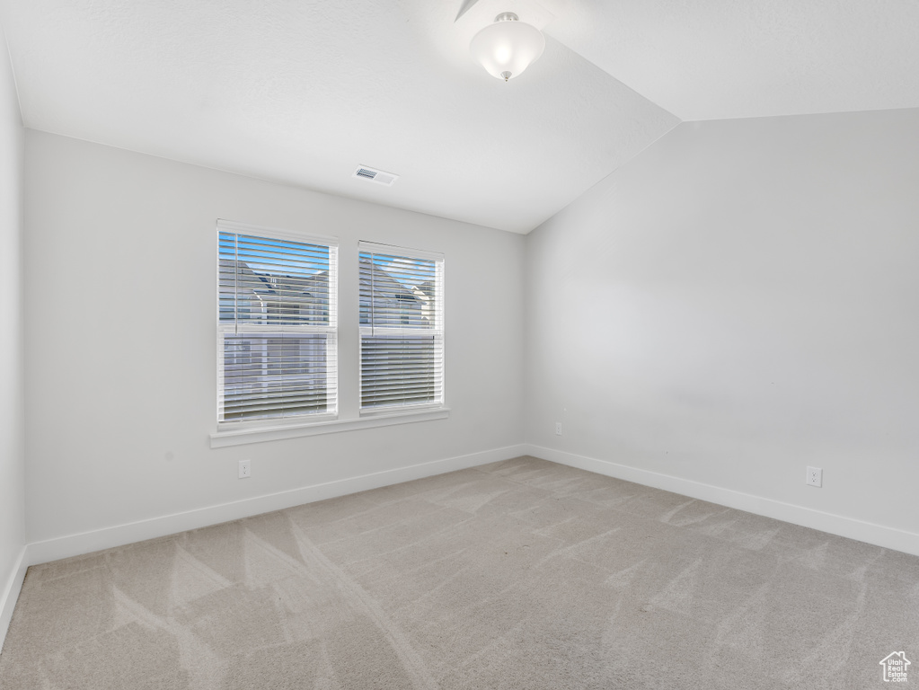 Unfurnished room featuring lofted ceiling, light carpet, and baseboards