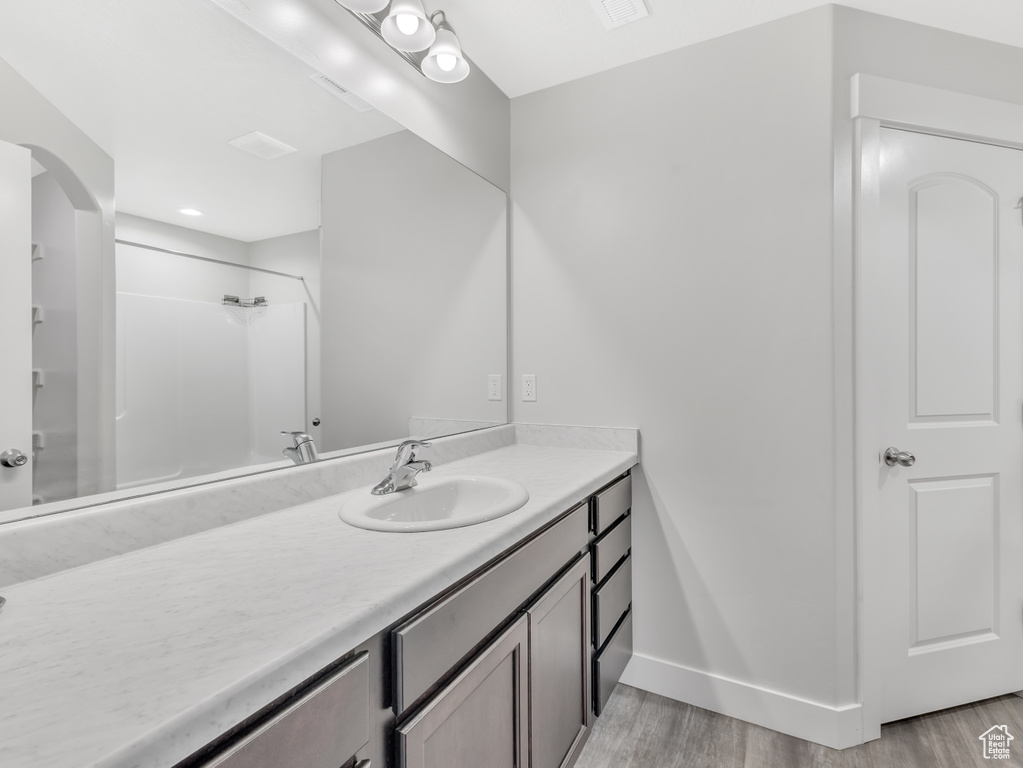 Bathroom featuring vanity, wood finished floors, a shower, and baseboards