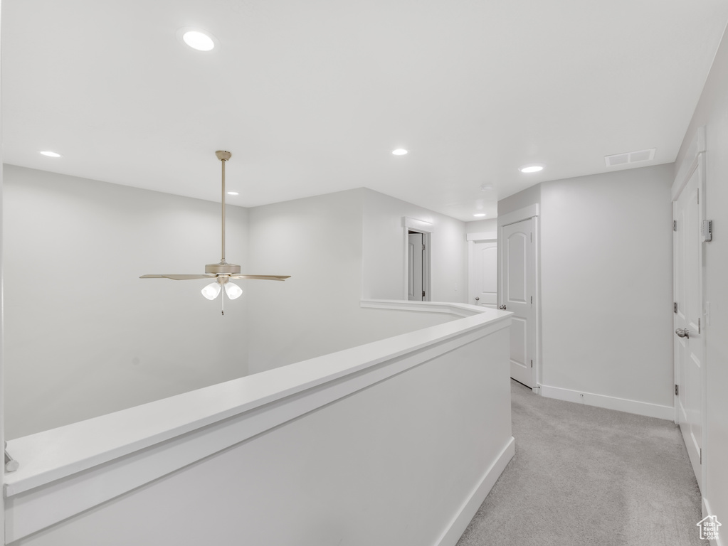 Hallway with light colored carpet, recessed lighting, and baseboards