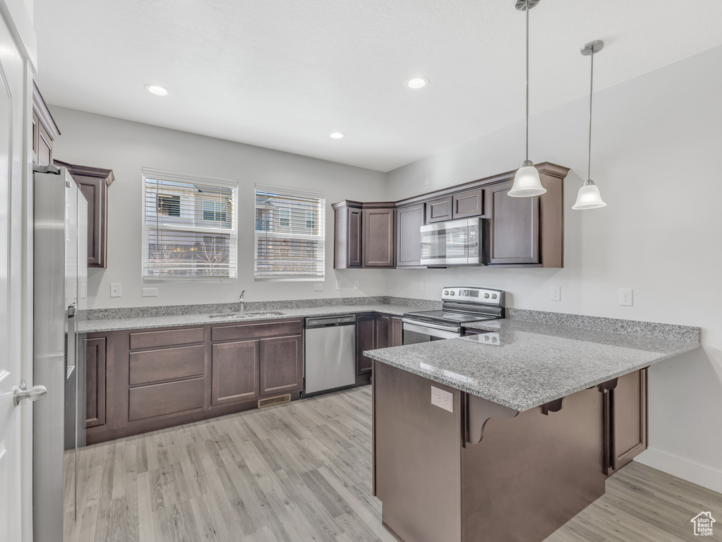 Kitchen featuring stainless steel appliances, a peninsula, light wood finished floors, a sink, and recessed lighting