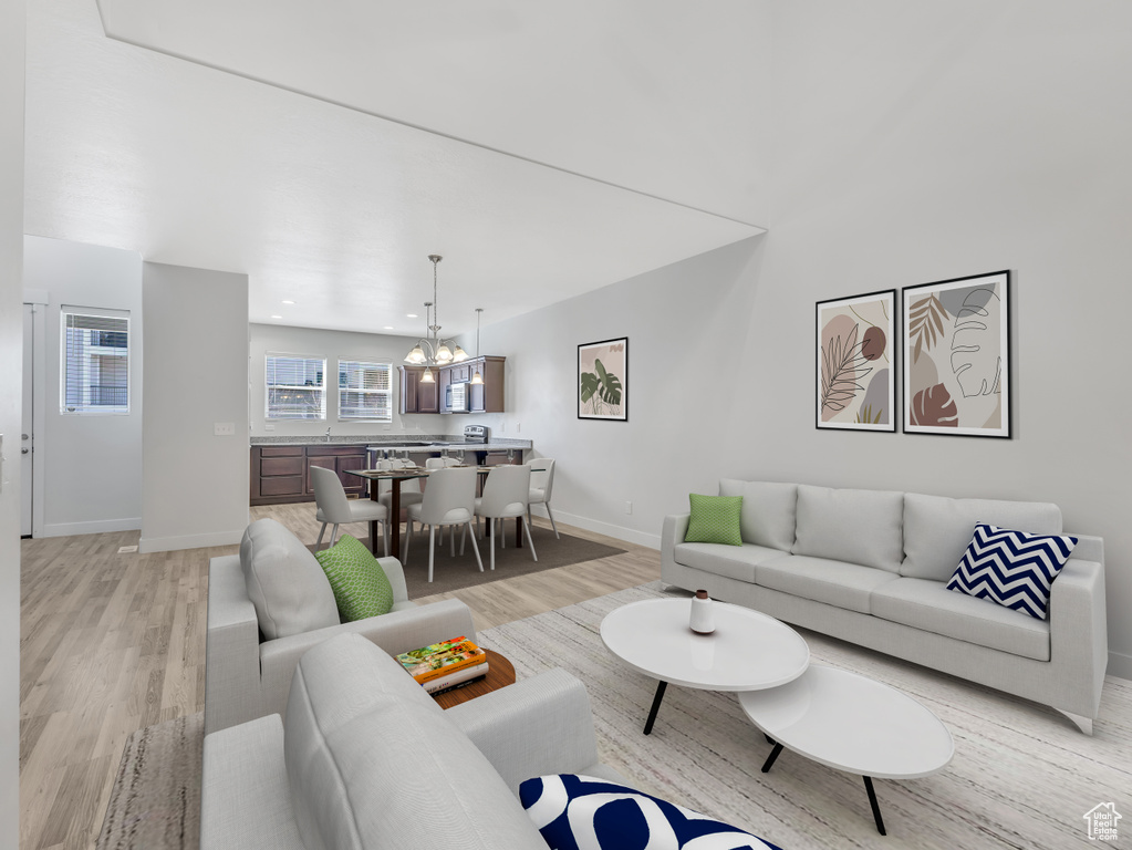 Living area with light wood finished floors, baseboards, a chandelier, and recessed lighting
