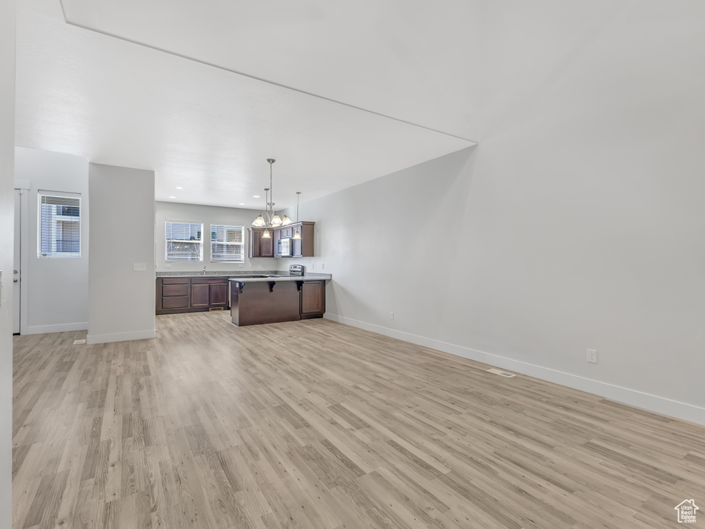 Kitchen with open floor plan, a chandelier, light wood-type flooring, baseboards, and recessed lighting