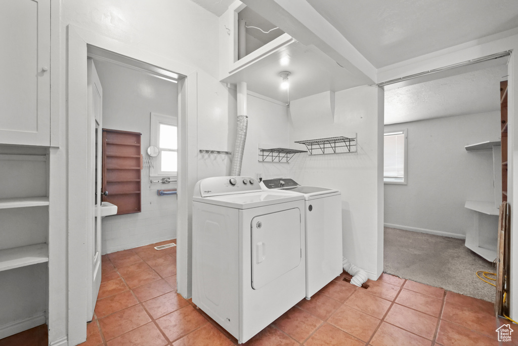 Laundry room featuring washer and dryer, light tile patterned floors, and light colored carpet