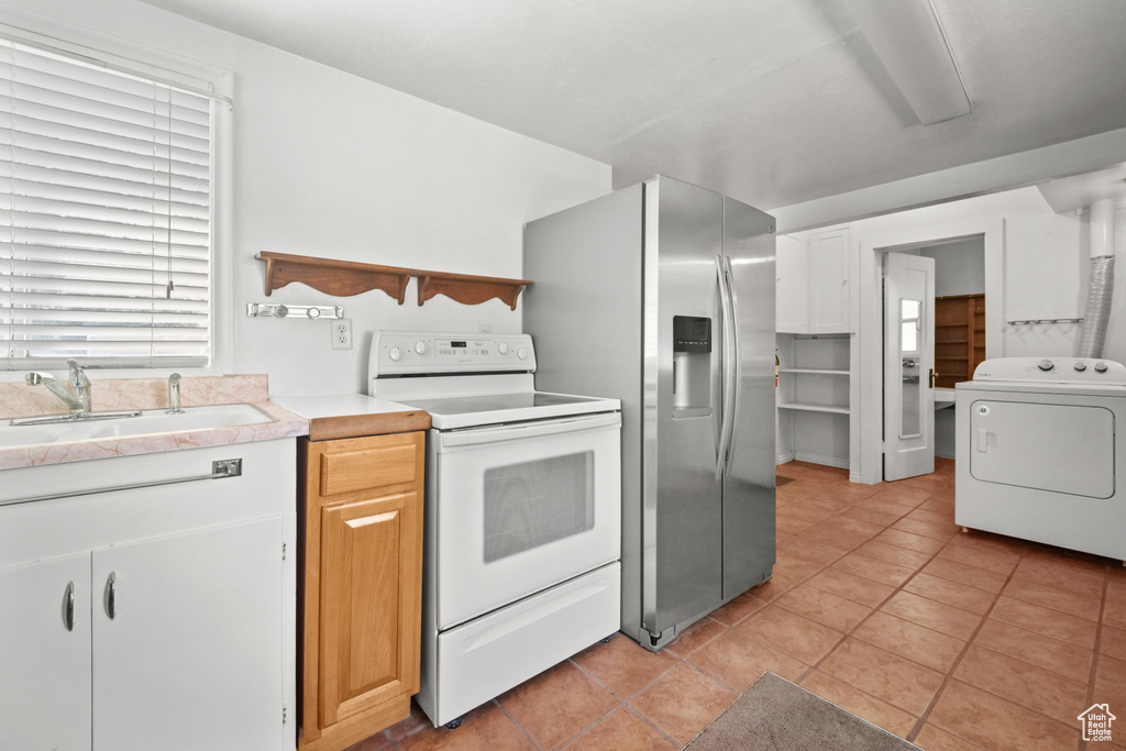 Kitchen with washer / clothes dryer, white range with electric cooktop, a sink, and light tile patterned floors