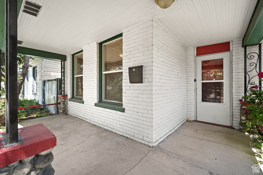 Doorway to property featuring a porch and brick siding