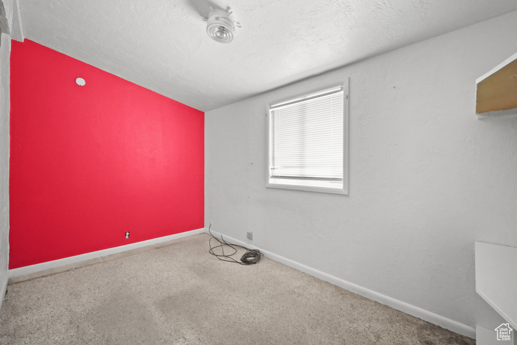 Spare room with carpet flooring, baseboards, and a textured ceiling