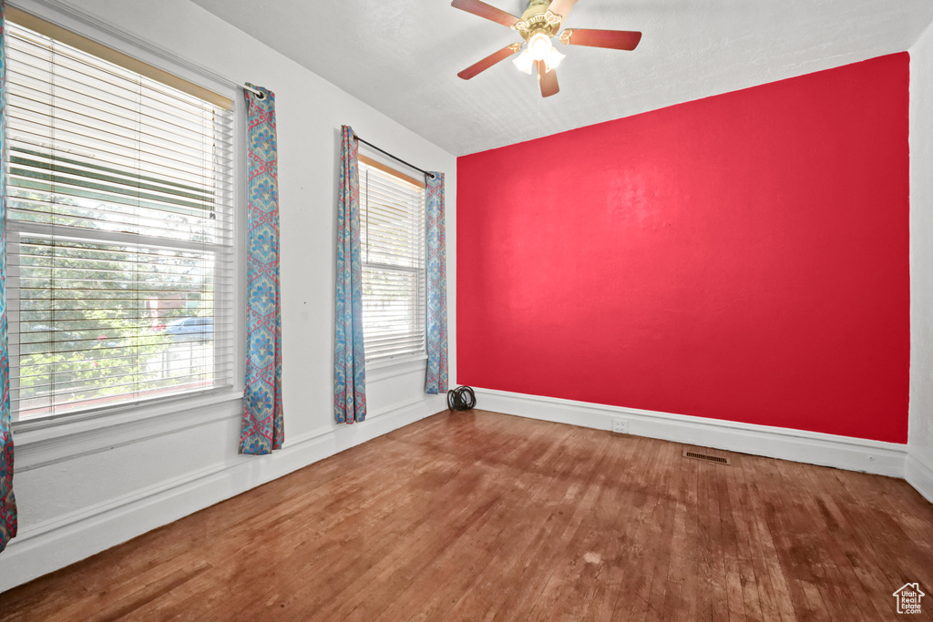 Spare room with wood finished floors, ceiling fan, and baseboards