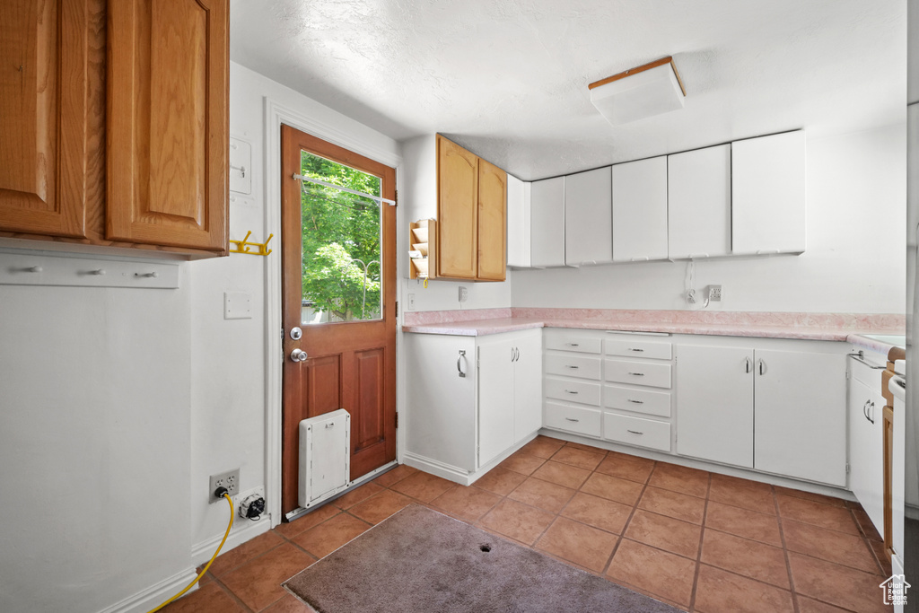 Kitchen with light tile patterned flooring, light countertops, and heating unit