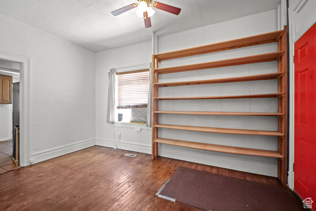 Unfurnished bedroom featuring wood-type flooring, a ceiling fan, and baseboards