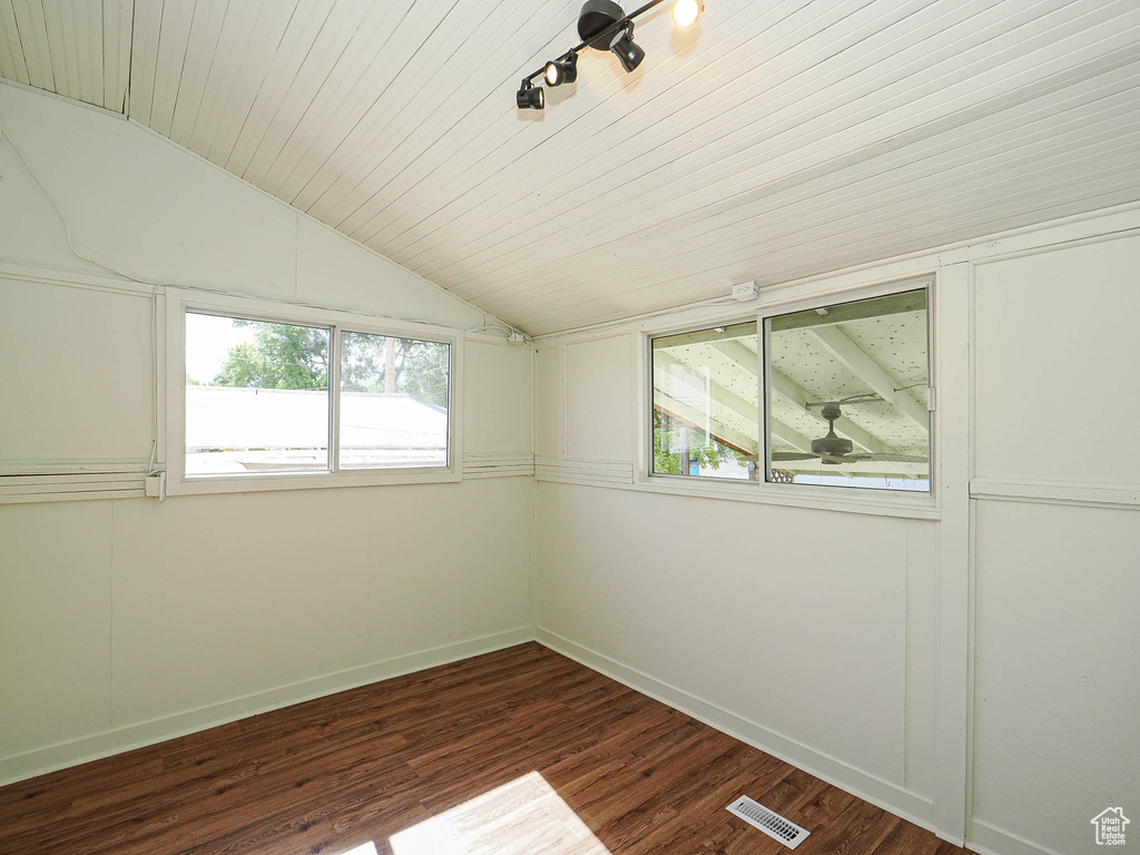 Spare room with lofted ceiling, baseboards, and dark wood-style flooring