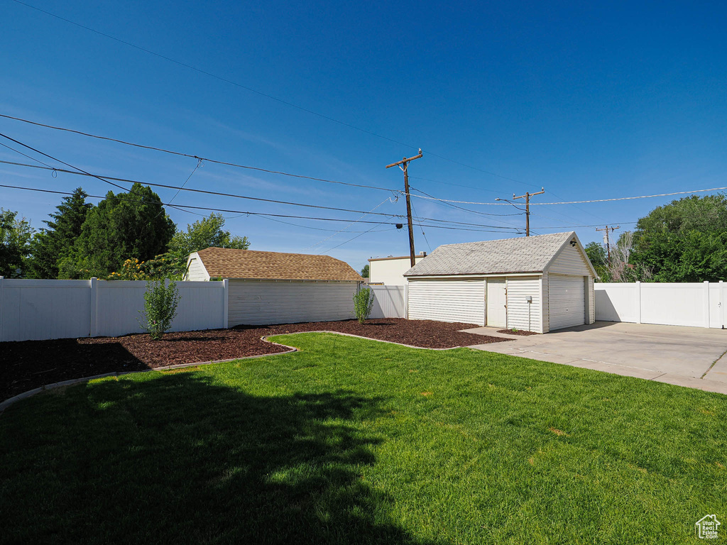 View of yard featuring a garage, an outbuilding, and concrete driveway