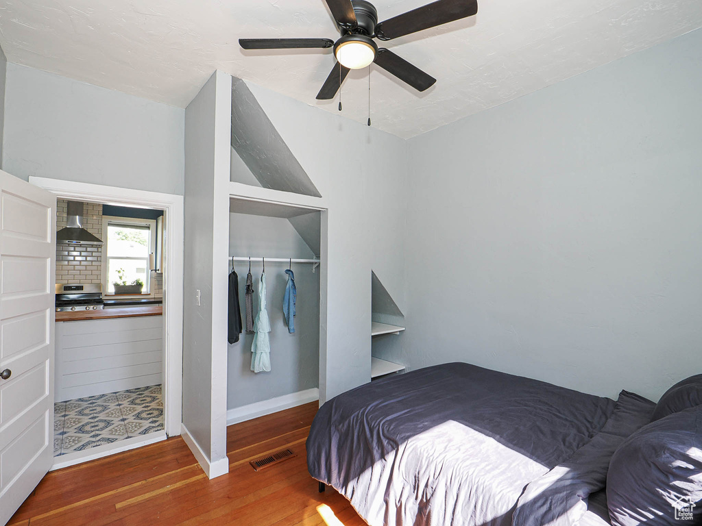 Bedroom with a closet, wood finished floors, baseboards, and ceiling fan