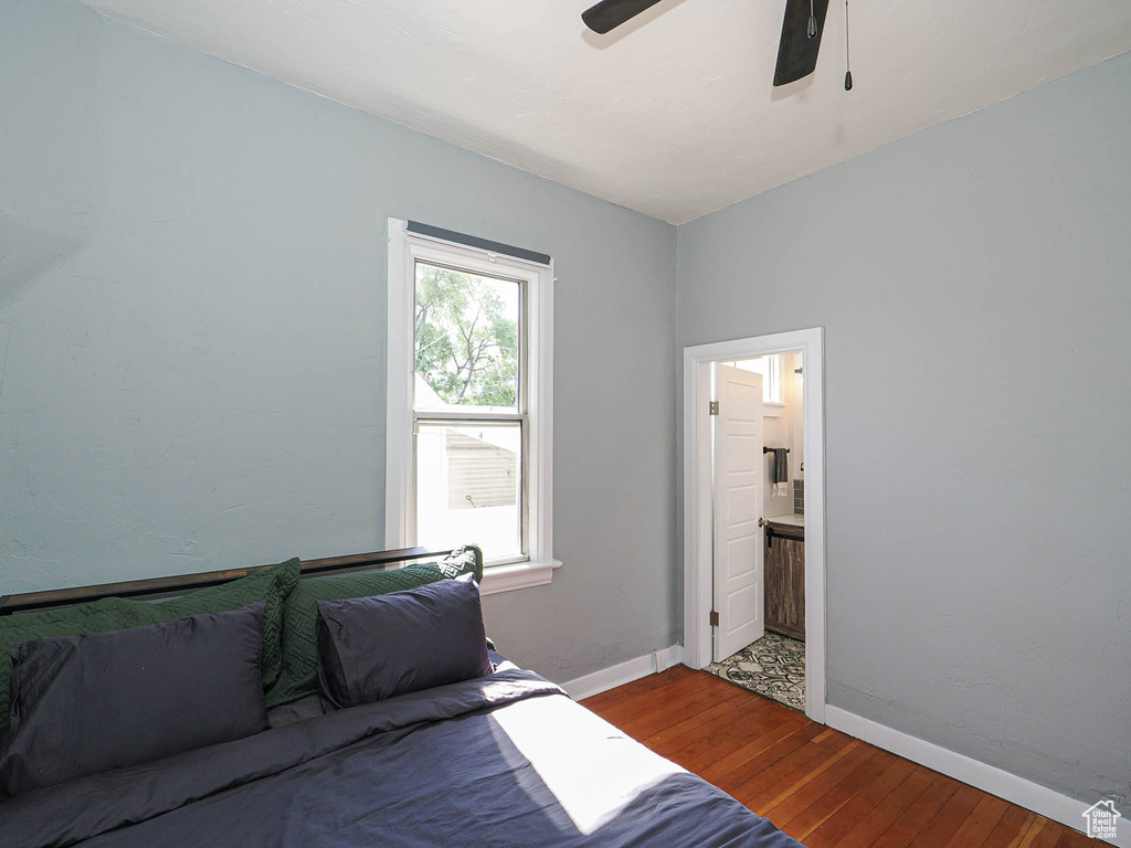 Bedroom with hardwood / wood-style flooring, baseboards, ensuite bath, and ceiling fan