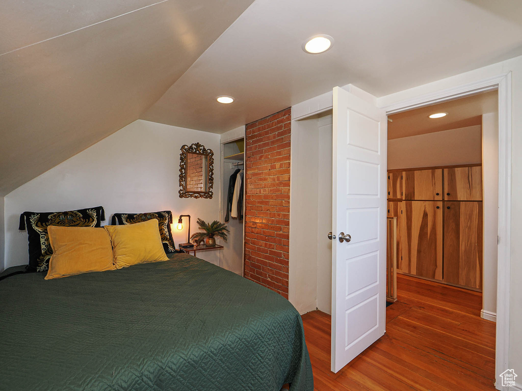 Bedroom with wood finished floors, recessed lighting, vaulted ceiling, and a closet