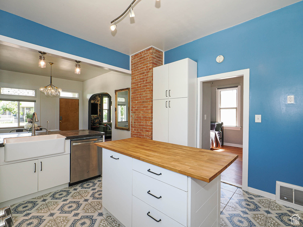 Kitchen with dishwasher, a sink, wooden counters, light tile patterned flooring, and arched walkways