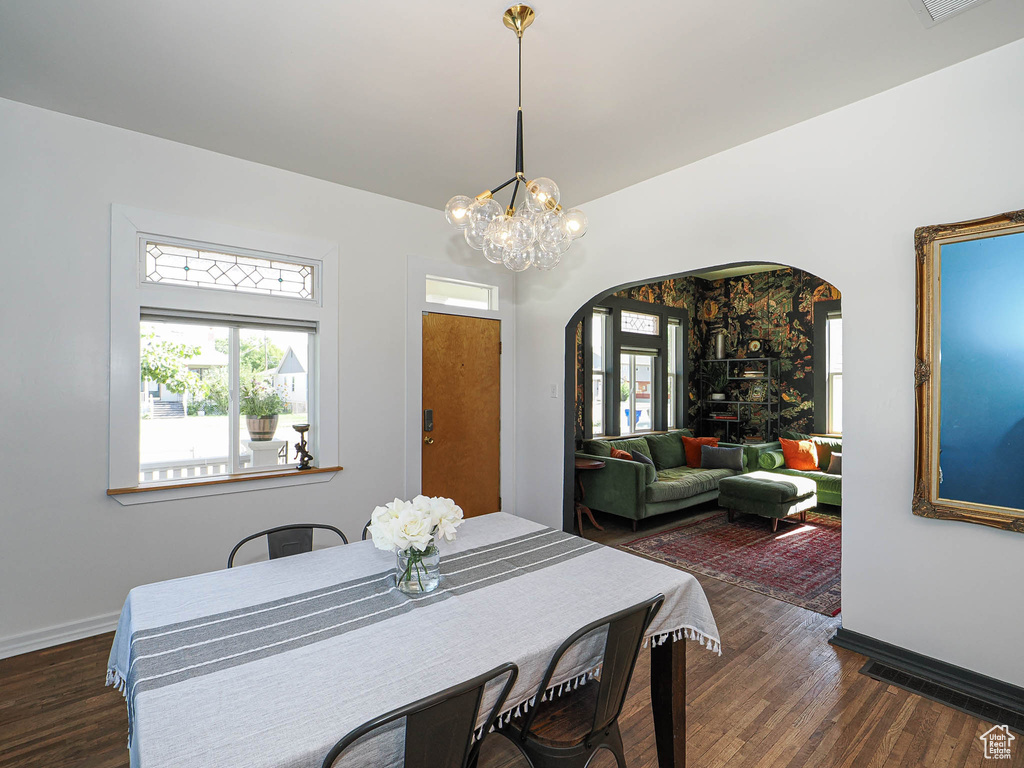Dining room featuring arched walkways, wood finished floors, baseboards, and a chandelier