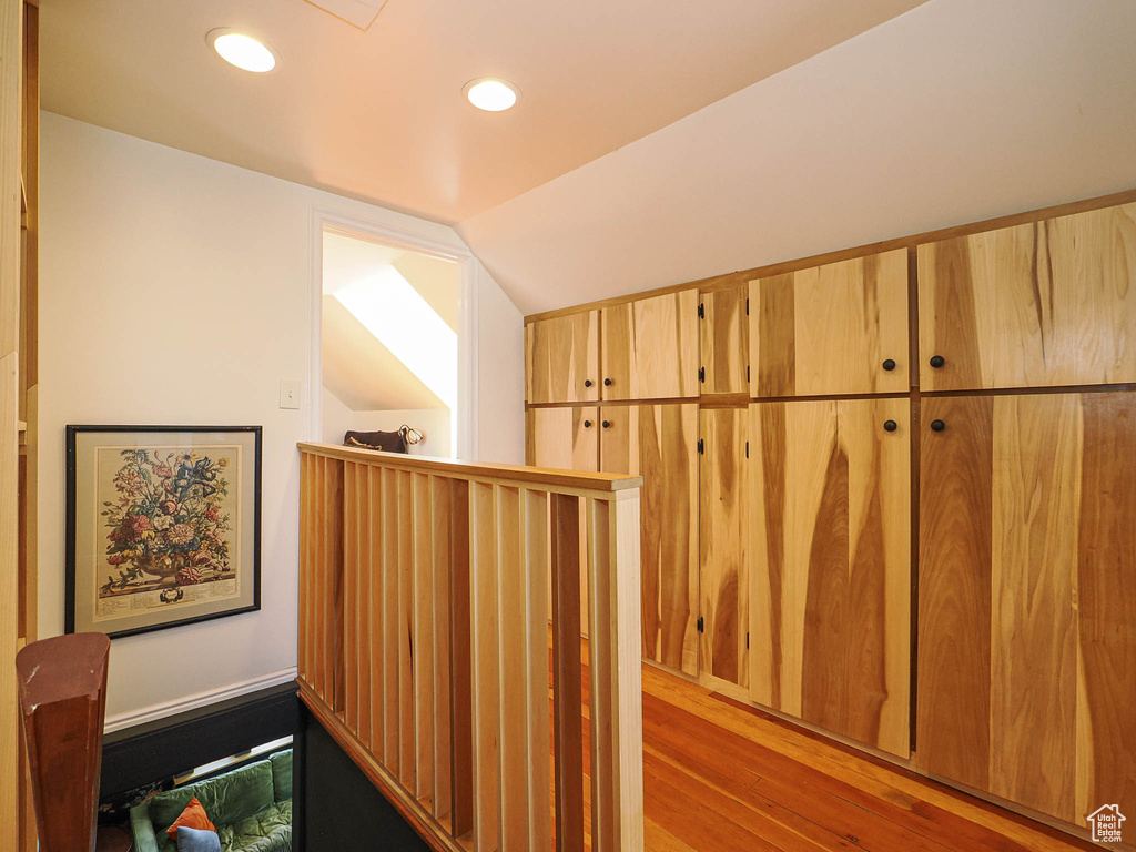 Corridor with wood finished floors, lofted ceiling, and recessed lighting