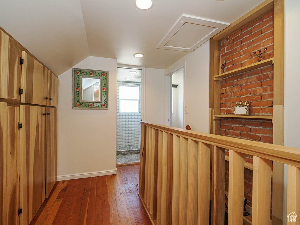 Corridor featuring dark wood-style floors, baseboards, attic access, and vaulted ceiling