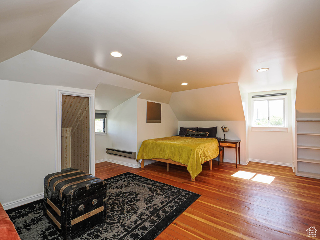 Bedroom with baseboard heating, baseboards, hardwood / wood-style floors, vaulted ceiling, and recessed lighting