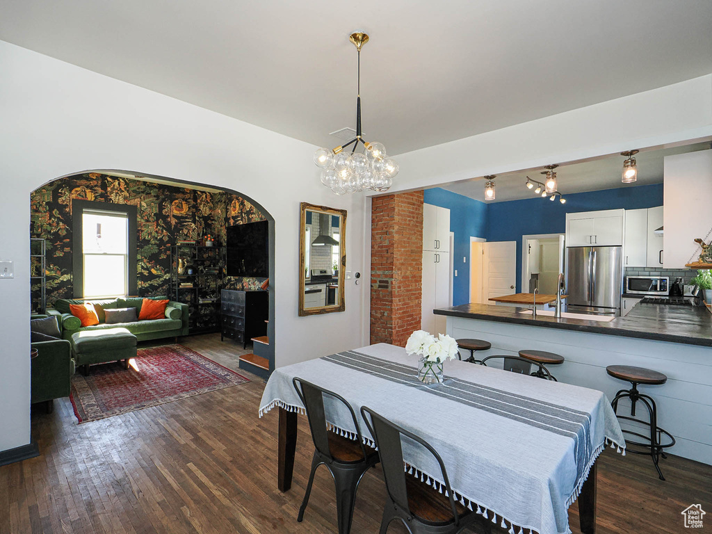 Dining space featuring dark wood-style floors, arched walkways, and a chandelier