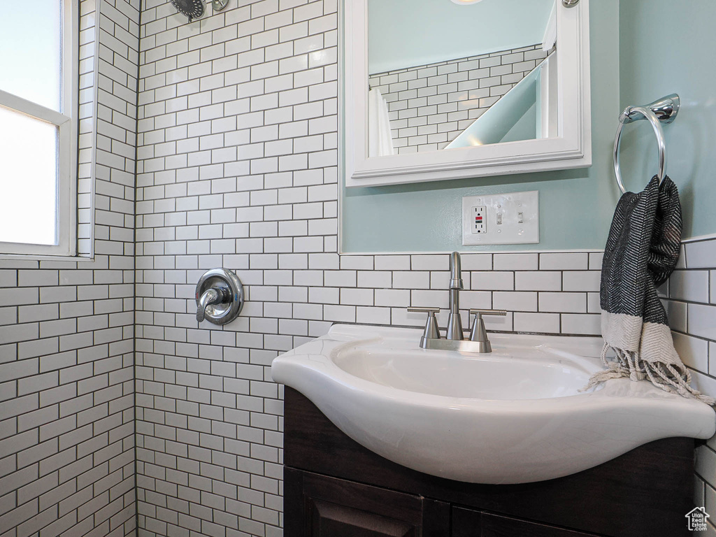 Full bathroom with tiled shower, vanity, and tile walls