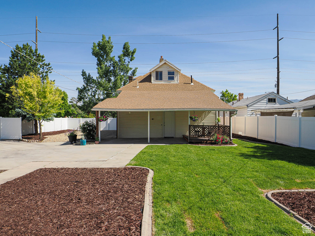 Rear view of property with concrete driveway, roof with shingles, and a chimney