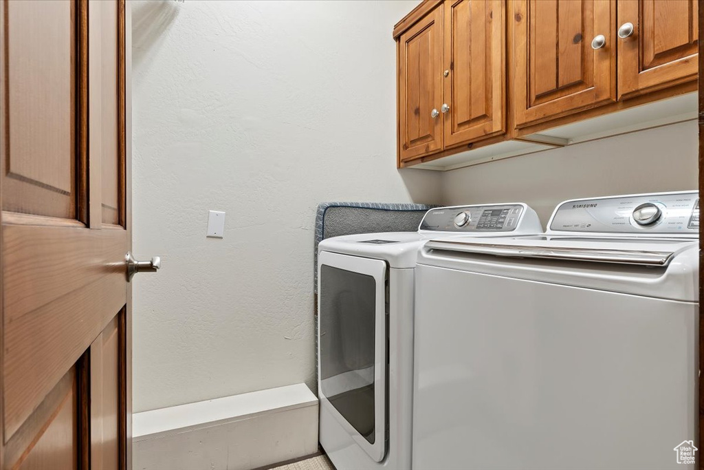Clothes washing area featuring washing machine and dryer and cabinet space