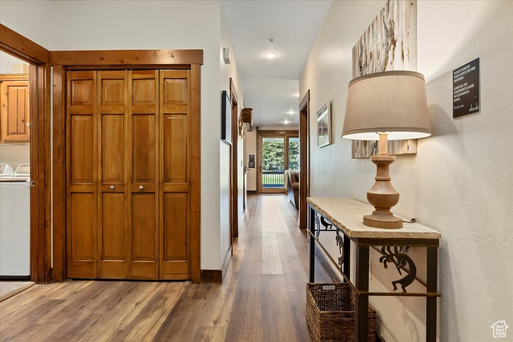 Corridor with washer and clothes dryer, wood finished floors, and baseboards