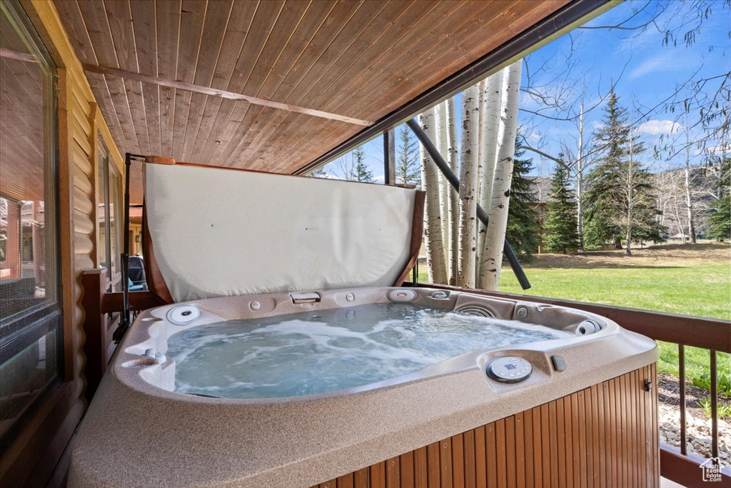 Wooden deck with a hot tub and a lawn