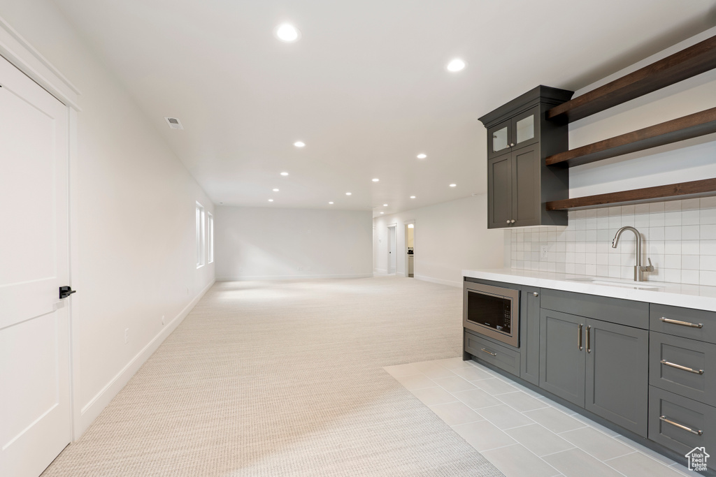 Kitchen featuring a sink, stainless steel microwave, recessed lighting, open shelves, and light countertops