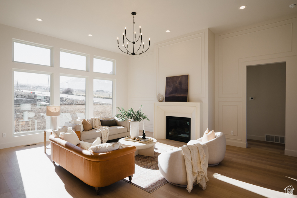 Living area with a chandelier, wood finished floors, a glass covered fireplace, recessed lighting, and baseboards