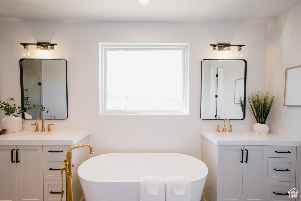 Bathroom featuring two vanities, a freestanding bath, and a tile shower
