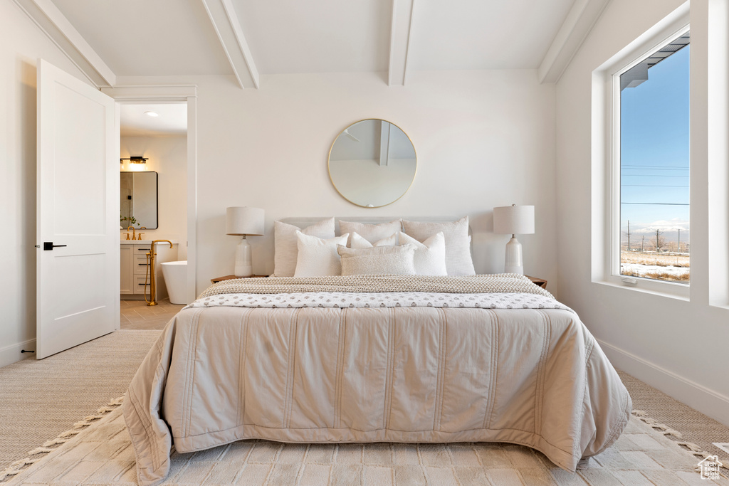 Bedroom featuring beamed ceiling, ensuite bathroom, and baseboards