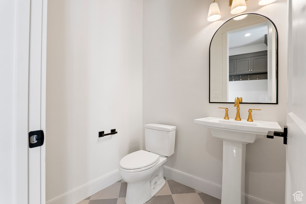 Bathroom with baseboards, toilet, and tile patterned floors