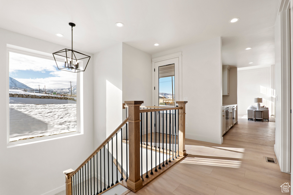Hallway with an upstairs landing, recessed lighting, a chandelier, light wood-type flooring, and baseboards