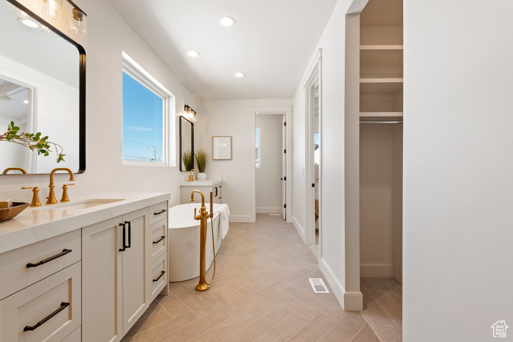 Full bathroom with vanity, recessed lighting, a soaking tub, and baseboards
