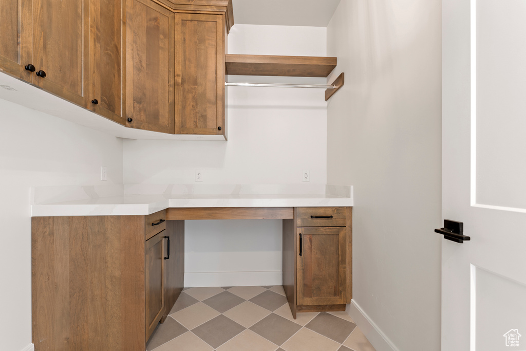 Kitchen featuring brown cabinetry, light countertops, light floors, and baseboards