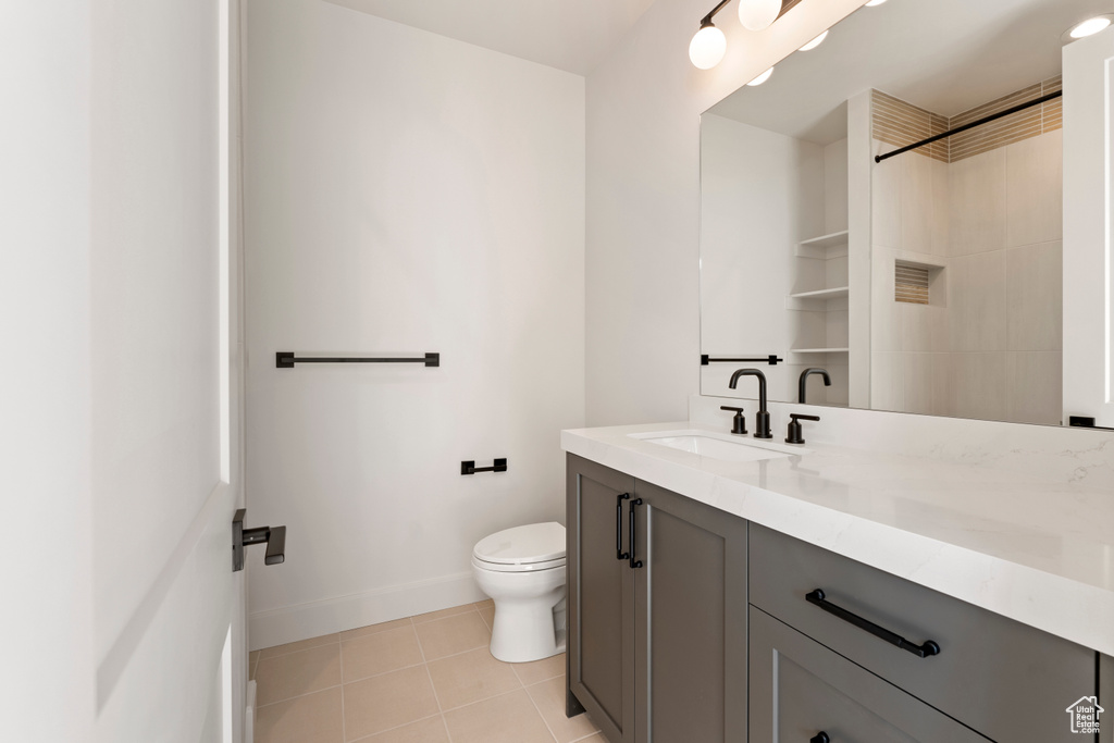Full bath with toilet, vanity, baseboards, tile patterned floors, and a shower