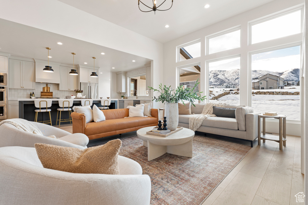 Living room featuring recessed lighting, light wood-type flooring, a mountain view, and a chandelier