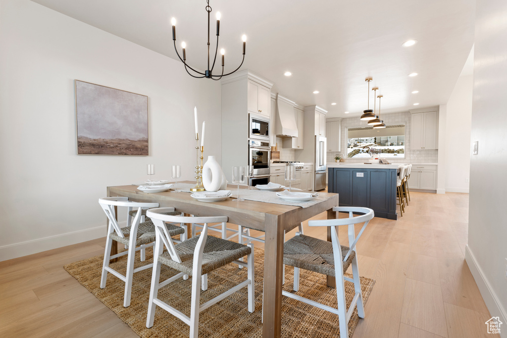 Dining room with light wood-type flooring, baseboards, recessed lighting, and a chandelier