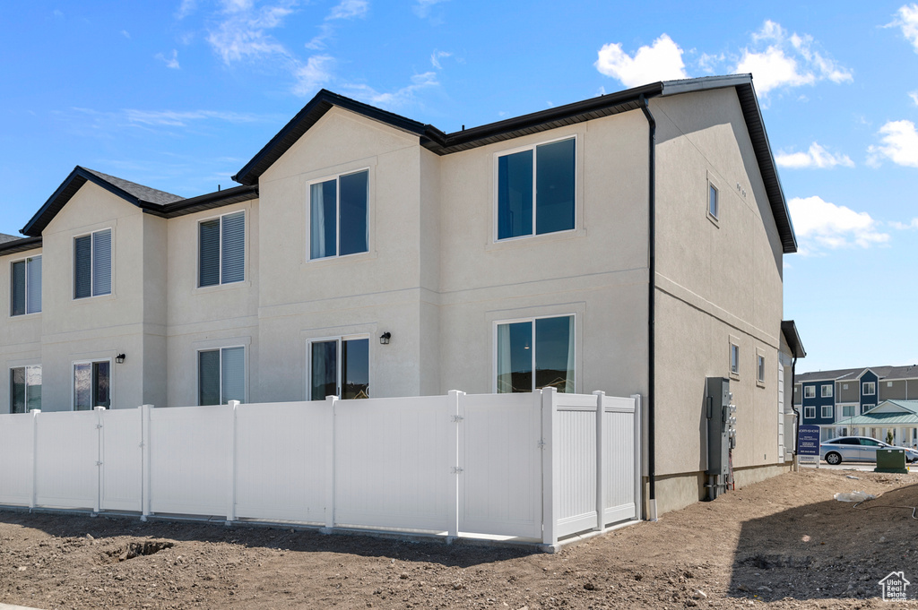 View of side of home featuring a gate and stucco siding