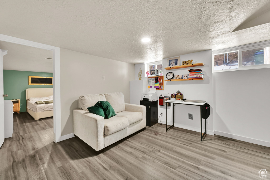Living area with light wood-style floors, baseboards, and a textured ceiling