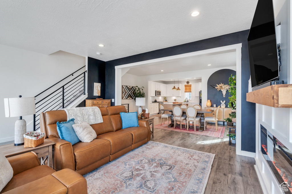 Living room featuring stairs, light wood-style flooring, baseboards, recessed lighting, and arched walkways