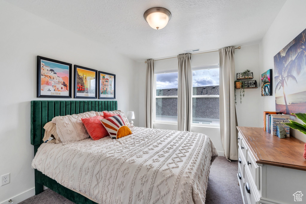 Carpeted bedroom featuring a textured ceiling and baseboards