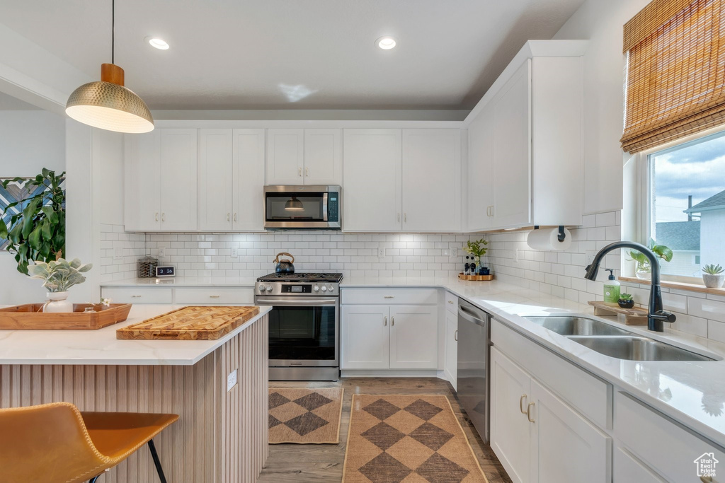 Kitchen featuring appliances with stainless steel finishes, a sink, white cabinetry, backsplash, and recessed lighting