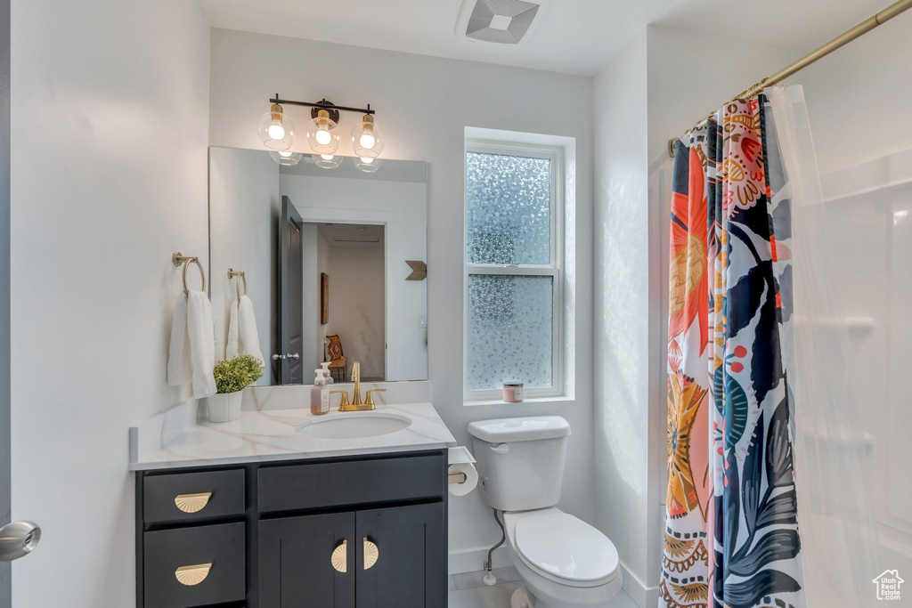 Full bathroom with vanity, toilet, and curtained shower