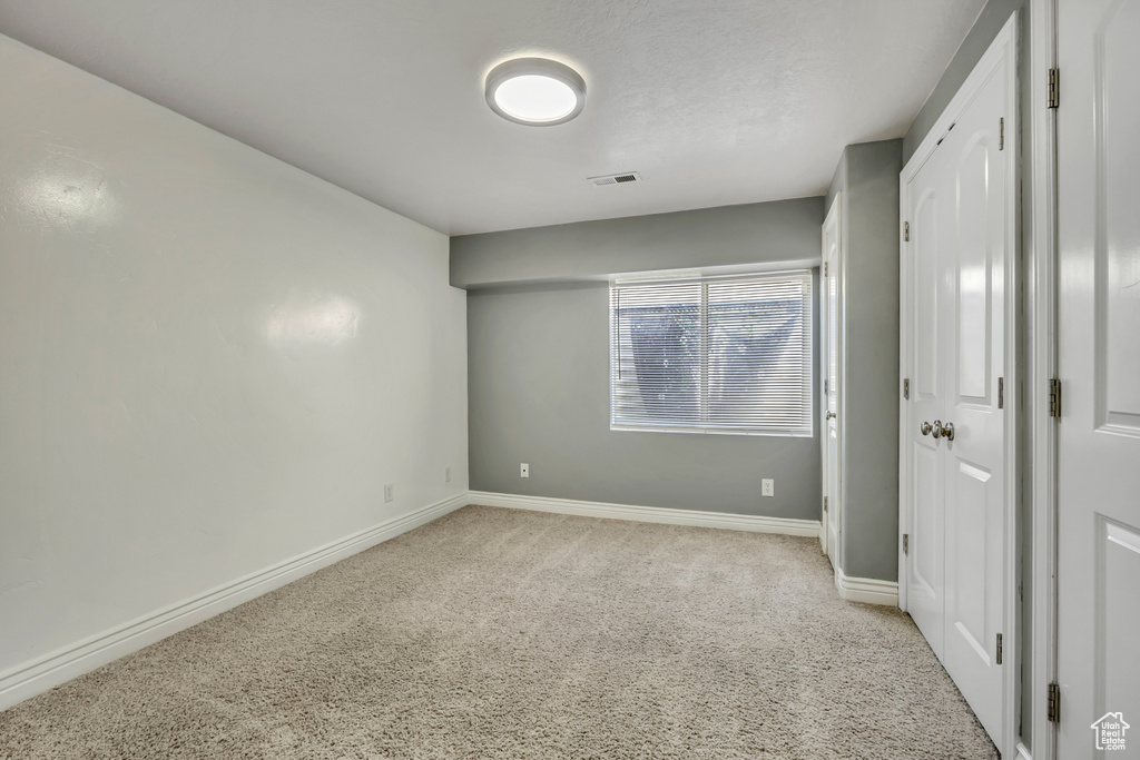 Unfurnished bedroom with light colored carpet and baseboards