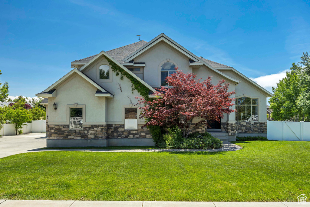View of front facade featuring stucco siding, stone siding, and driveway