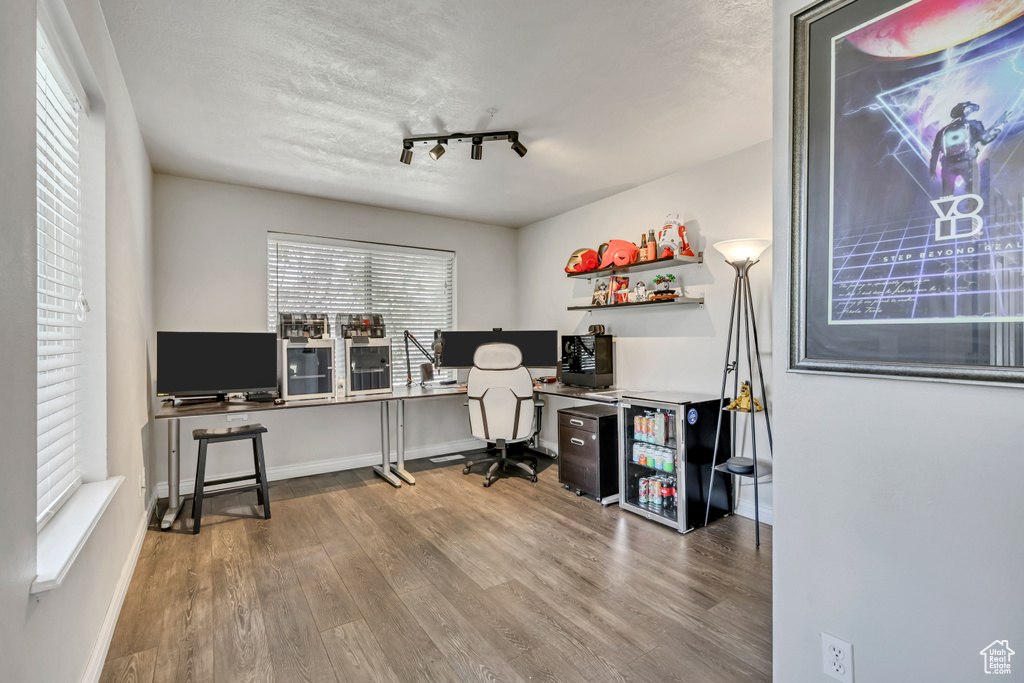 Office featuring wood finished floors, rail lighting, and baseboards