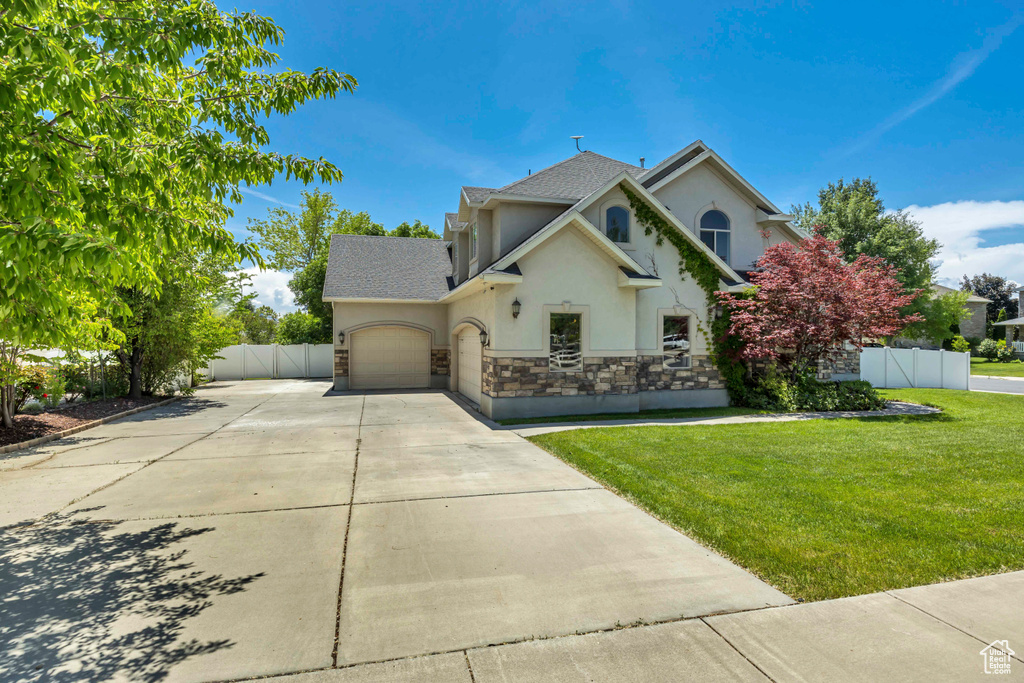 Traditional-style home with stucco siding, driveway, an attached garage, stone siding, and roof with shingles